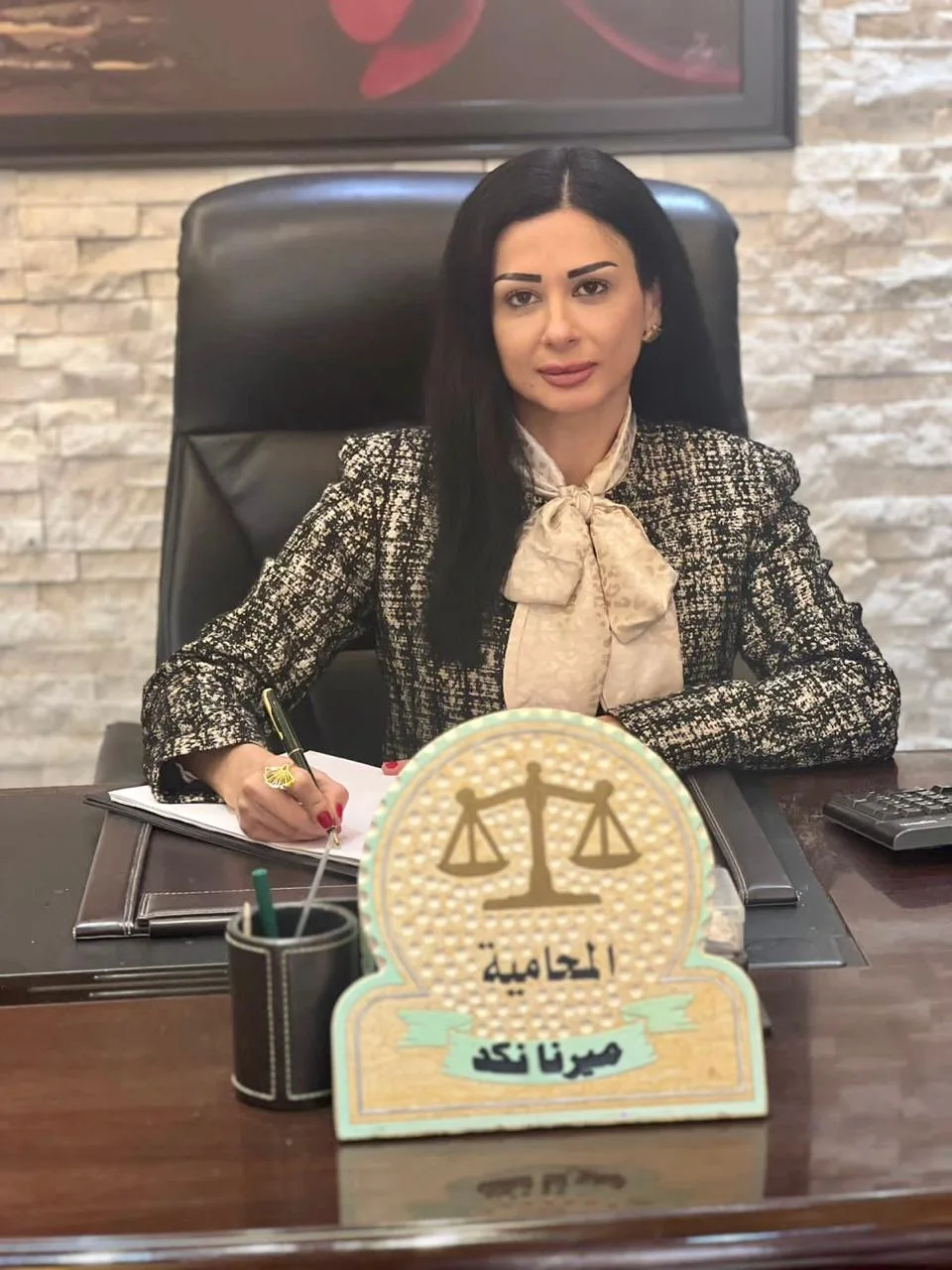 العمل على مكتب المحامية إلى جانب لوحة الاسم.