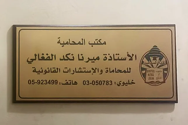 اللوحة على باب المكتب: مكتب المحامية ميرنا نكد للمحاماة والاستشارات القانونية، إلى جانب شعار نقابة المحامين.